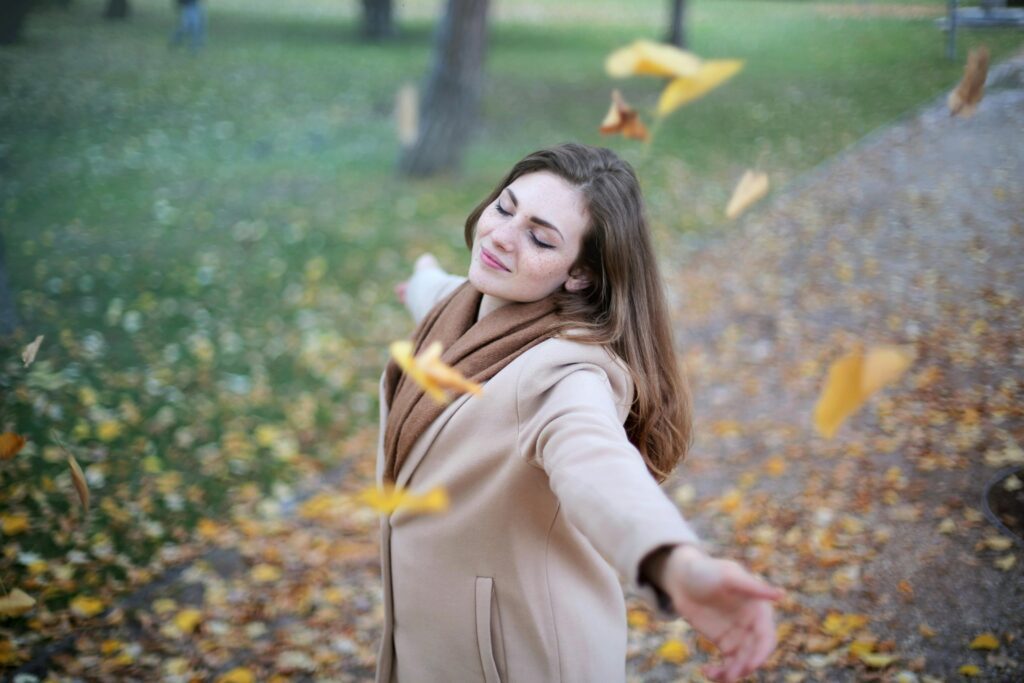 pexels-photo-712413-712413 Young woman with arms outstretched, delighting in fallen leaves in a Paris park during autumn daytime.
